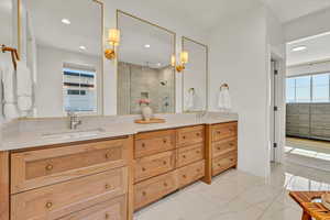 Bathroom with a sink, marble finish floor, a stall shower, and double vanity