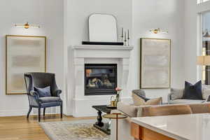 Living area featuring a glass covered fireplace, baseboards, and wood finished floors