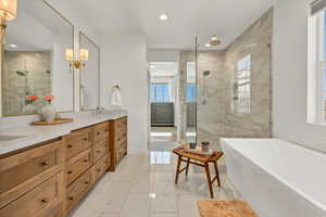 Bathroom featuring a shower stall, double vanity, a soaking tub, marble finish floor, and a sink