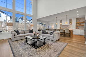 Living room with recessed lighting, light wood-style flooring, a high ceiling, and a healthy amount of sunlight