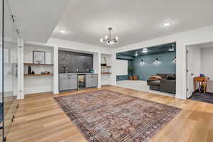 Living room with wine cooler, built in shelves, a bar, and light wood-style floors
