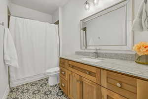 Bathroom featuring vanity, tile patterned floors, shower / bath combination with curtain, and toilet