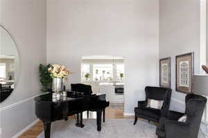 Living area with light wood-type flooring, a high ceiling, and hardwood floors.  Could also be a formal dining area.