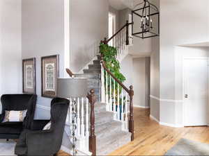 Stairs with a chandelier, wood finished floors and a towering ceiling.