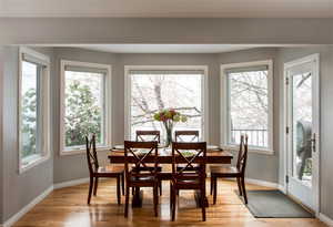 Dining space with light wood finished floors and a healthy amount of sunlight.