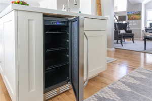 Kitchen featuring light wood-style flooring, wine cooler, and white cabinetry.