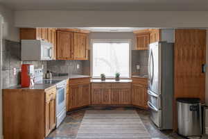 Mother -in-law kitchen with white appliances, tasteful backsplash, and stone tile flooring.