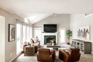 Living area featuring high vaulted ceiling, a premium fireplace, and light colored carpet