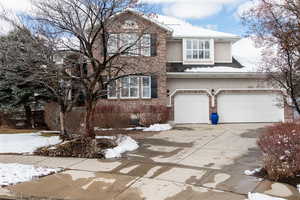 Traditional-style 2-story house with driveway, brick siding, an attached 3 car garage, and stucco siding.