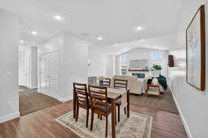 Dining area featuring lofted ceiling, a glass covered fireplace, wood finished floors, and recessed lighting