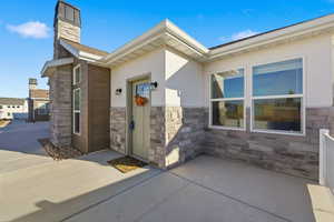 Entrance to property with stone siding, stucco siding, and a chimney
