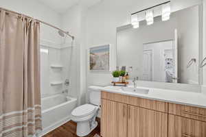 Bathroom with shower / tub combo with curtain, dark wood-style flooring, and vanity