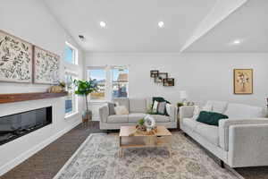 Living room with carpet floors, a glass covered fireplace, and recessed lighting