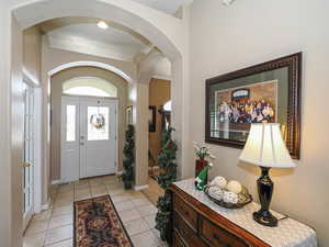 Foyer entrance with visible vents, light tile patterned floors, arched walkways, and baseboards