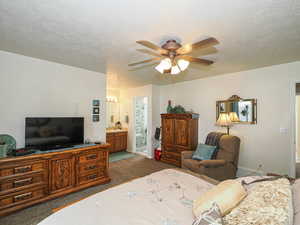 Bedroom featuring ensuite bath, carpet floors, and a textured ceiling