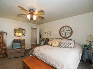 Bedroom with baseboards, a textured ceiling, a ceiling fan, and carpet floors