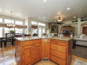 Kitchen with light stone counters, open floor plan, a textured ceiling, and light wood-type flooring