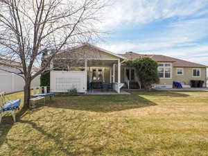 Rear view of property with fence, entry steps, a lawn, french doors, and a patio