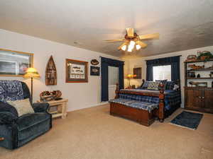 Bedroom with visible vents, carpet floors, a textured ceiling, and a ceiling fan