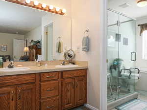 Bathroom with double vanity, visible vents, a stall shower, and a sink