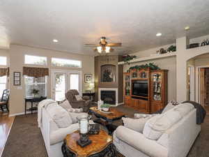 Living room with baseboards, arched walkways, a textured ceiling, and a fireplace