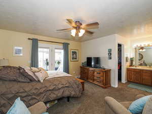 Carpeted bedroom with a ceiling fan, access to outside, a textured ceiling, a closet, and a spacious closet