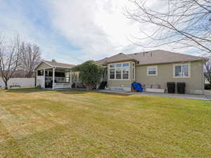 Rear view of property with a jacuzzi, a yard, a patio area, and fence