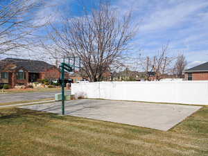 View of basketball court featuring a yard and fence