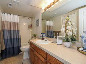 Full bath featuring vanity, toilet, visible vents, and a textured ceiling