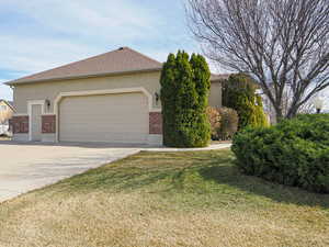 View of front of home with brick siding, stucco siding, concrete driveway, and a front lawn