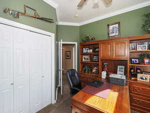 Office area featuring crown molding, dark carpet, and ceiling fan