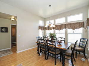 Dining space featuring baseboards, light wood-type flooring, and a chandelier