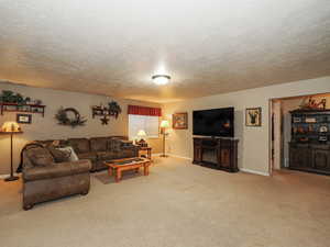 Living area with baseboards, carpet floors, a textured ceiling, and a fireplace