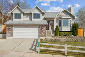 Split level home with brick siding, driveway, fence, and an attached garage