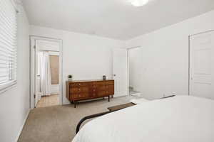 Bedroom with light carpet, ensuite bathroom, and baseboards