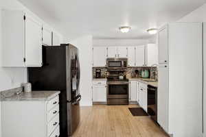 Kitchen featuring light countertops, backsplash, appliances with stainless steel finishes, light wood finished floors, and a sink