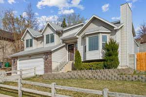View of front of property featuring an attached garage, a fenced front yard, and driveway