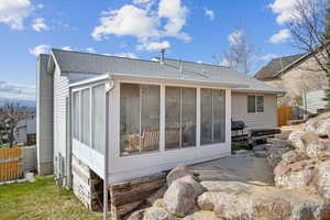 Back of property with a sunroom, roof with shingles, and fence