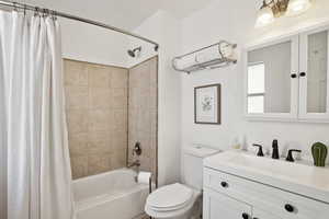 Bathroom with shower / bath combination with curtain, vanity, and toilet