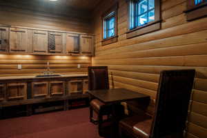 Office with log walls, a sauna, and dark carpet