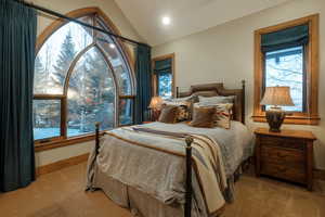 Carpeted bedroom with lofted ceiling and multiple windows