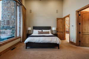 Bedroom featuring light carpet and a towering ceiling