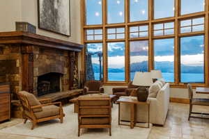 Living room with a fireplace, stone tile flooring, a high ceiling, and a water and mountain view