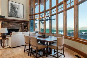 Dining area featuring a fireplace, a water view, and light stone finish flooring
