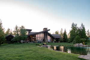 Back of property at dusk featuring a yard and a water view