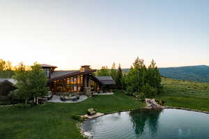 Back of property at dusk with a patio and a yard