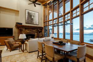 Dining room with a towering ceiling, a stone fireplace, a chandelier, ceiling fan, and a water and mountain view