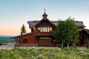 View of front of property featuring roof mounted solar panels, an attached garage, stone siding, and driveway