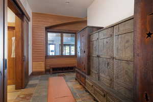 Mudroom featuring stone tile flooring and wooden walls