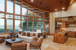 Living area with wooden ceiling, a towering ceiling, recessed lighting, stone tile flooring, and a mountain view